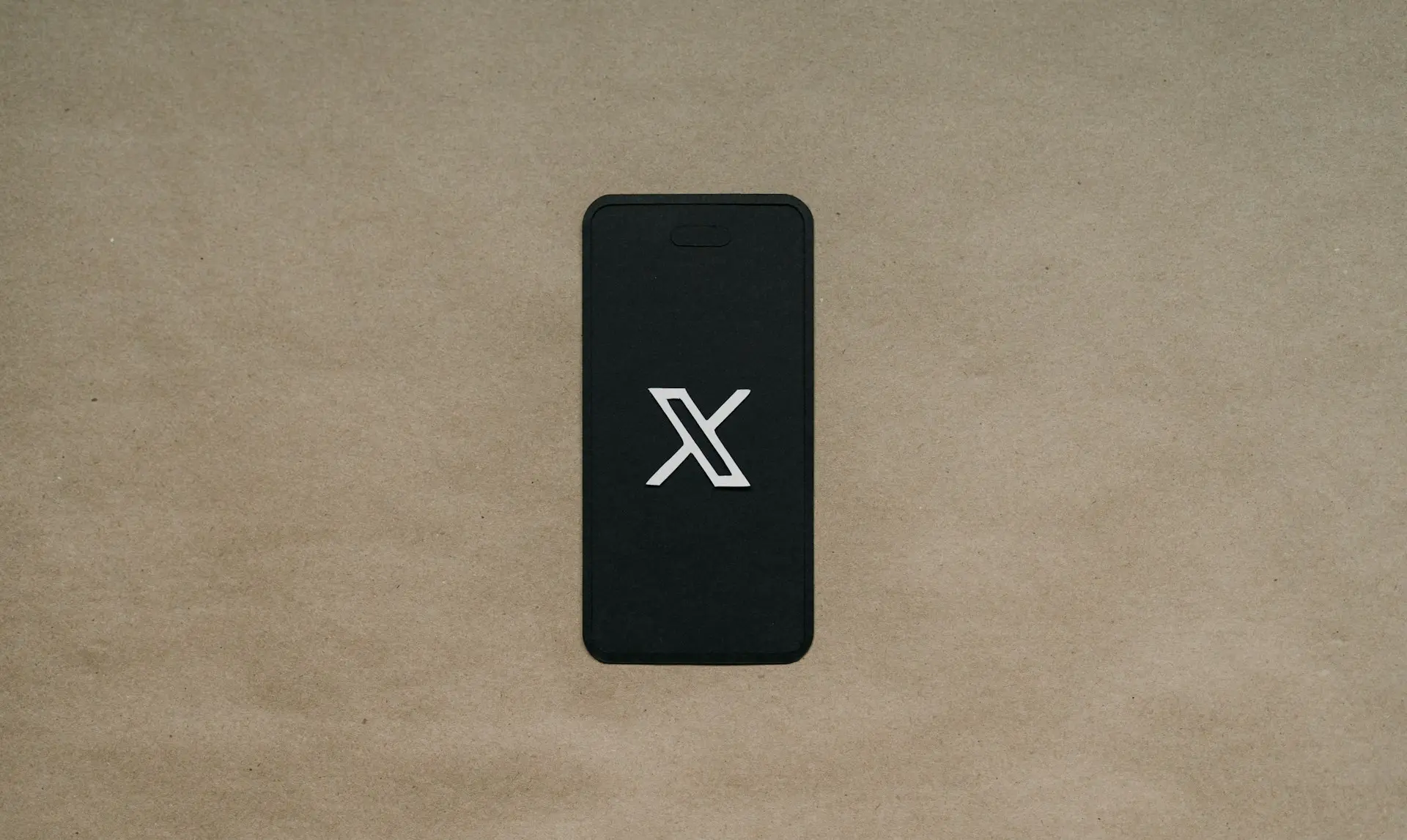 a black cell phone laying on top of a brown surface